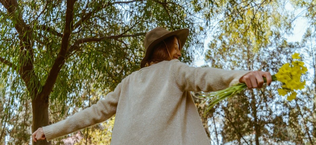 woman in brown long sleeve shirt and brown skirt holding green leaf during daytime