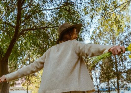 woman in brown long sleeve shirt and brown skirt holding green leaf during daytime