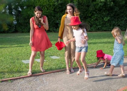 A joyous family experience in a lush Portugal park, featuring playful activities between young girls and adults.
